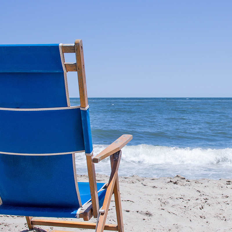 Low-profile blue beach chair positioned on the sand overlooking the ocean.